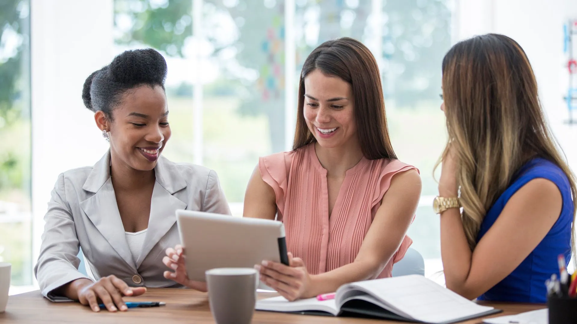 Trois professionnelles échangeant autour d’une tablette lors d’une réunion